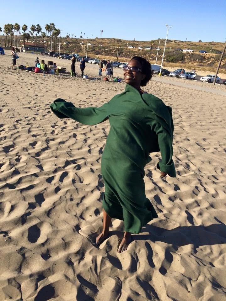 Spinning on the beach in a green coat